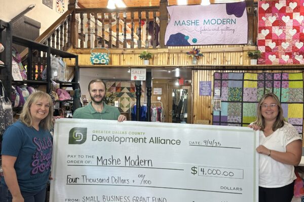 Grace Grob from the Greater Dallas County Development Alliance presents a check for $4,000 to Mashe Modern, a recipient of the Small Business Grant Fund.