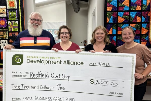Rachel Wacker and Grace Grob from the Greater Dallas County Development Alliance present a check for $3,000 to Redfield Quilt Shop, a recipient of the Small Business Grant Fund.
